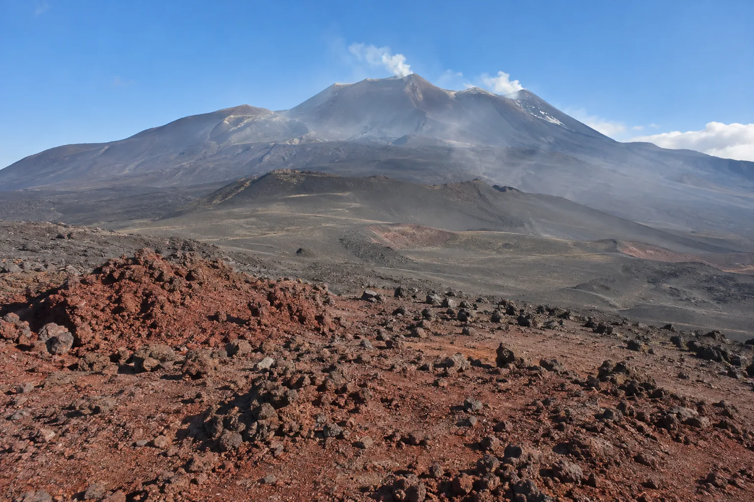 Etna, la cenere degli ultimi giorni colora di rosso il suolo a Piano del Lago